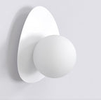 Witte wandlamp met ronde bol op een keivormige witte achterplaat tegen een lichte muur