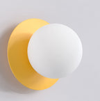 Wandlamp met matte witte bol voor een ronde oranje achterplaat tegen een lichte muur