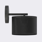 Zwarte wandlamp met ronde wandplaat, arm en cilindrische geperforeerde stoffen kap, zijaanzicht