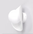 Witte wandlamp met ronde bol en lintvormig scherm aan een lichte wand