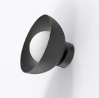 Zwarte wandlamp met schuin geplaatste komvorm en witte bolvormige lampenkap, gemonteerd op een lichte muur