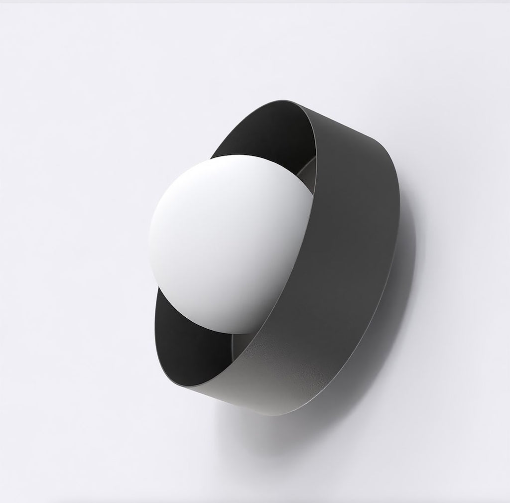 Zwarte wandlamp met witte bolkap in een gedraaide metalen band tegen een lichte muur