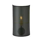 Zwarte wandlamp met halfronde geperforeerde stoffen kap waar het warme licht van de lamp doorheen schijnt