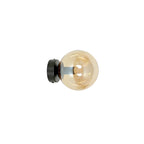 Zwarte wandlamp met ronde amberkleurige glazen bol aan een ronde zwarte wandplaat