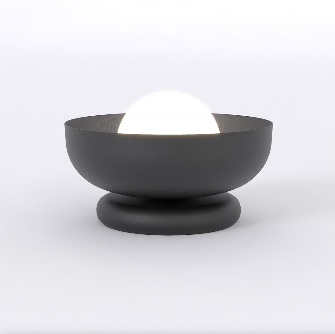 Zwarte tafellamp met een brede kom op een ronde voet en een verlichte witte glazen bol erin