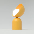 Oranje tafellamp met een halfronde schaal op een ronde sokkel en een lichtgevende witte bol