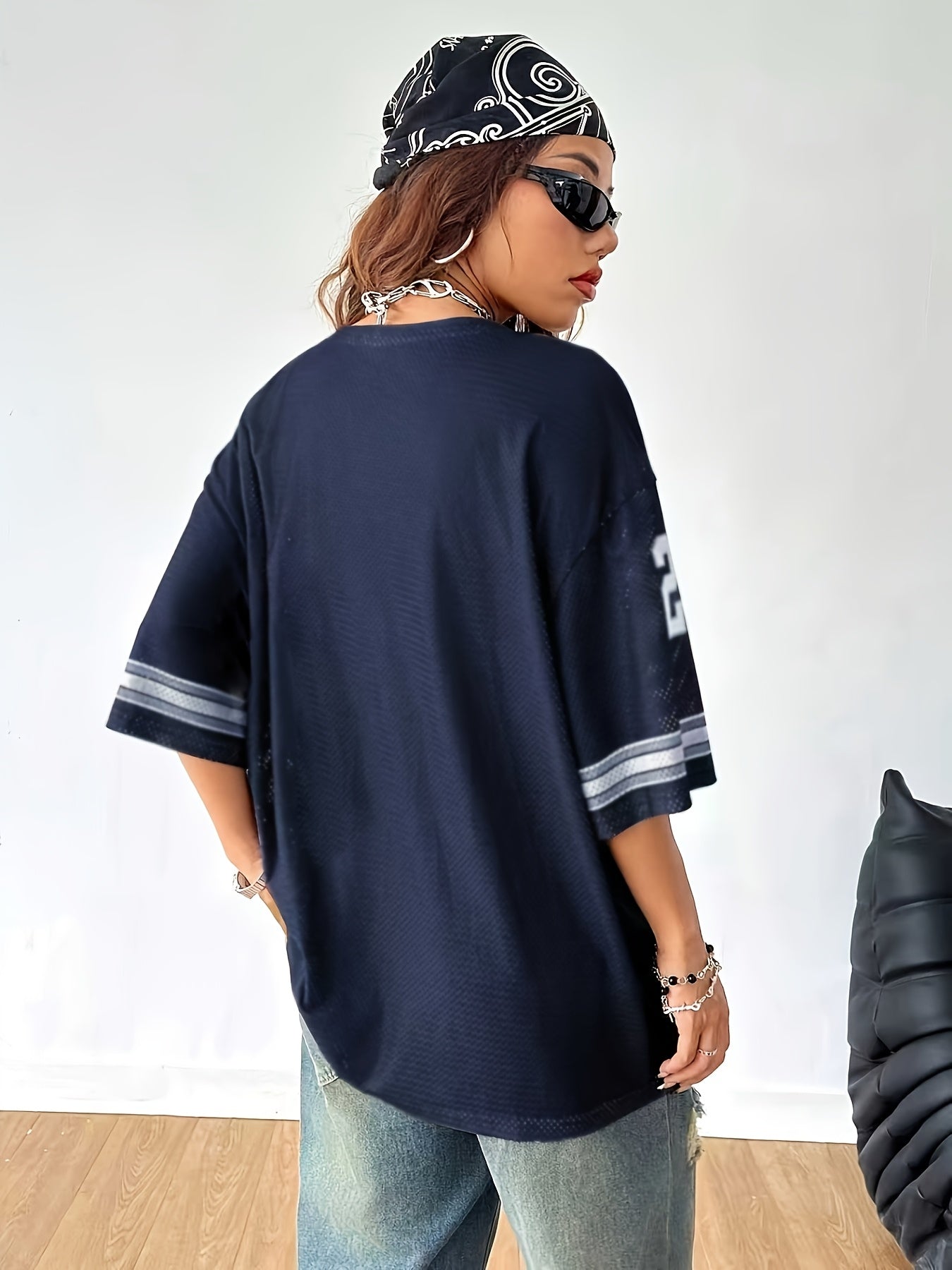 Women's streetwear oversized jersey shirt with number print and wide destroyed jeans – urban casual look