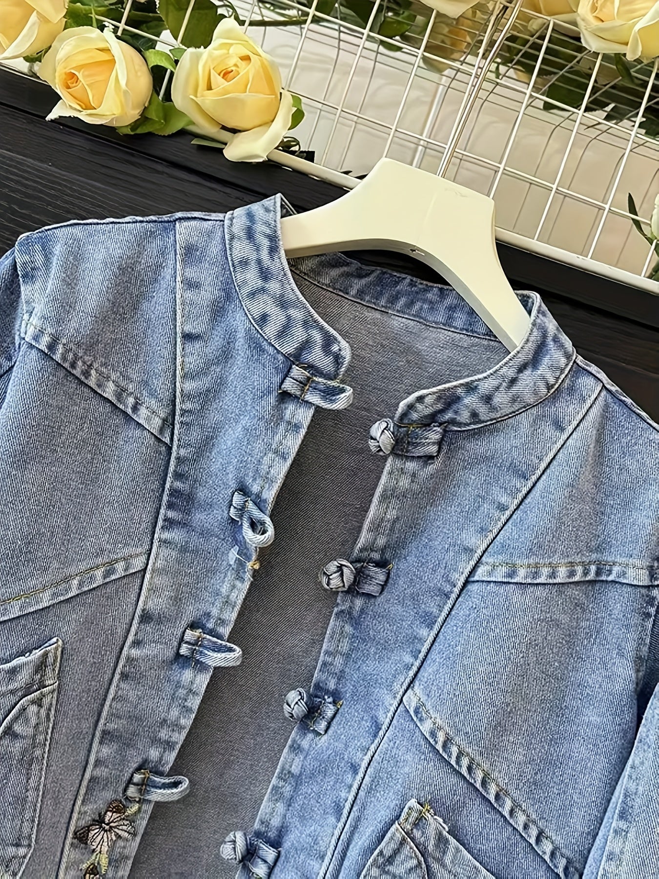 Women's denim jacket with stand-up collar, frog closures, and embroidery